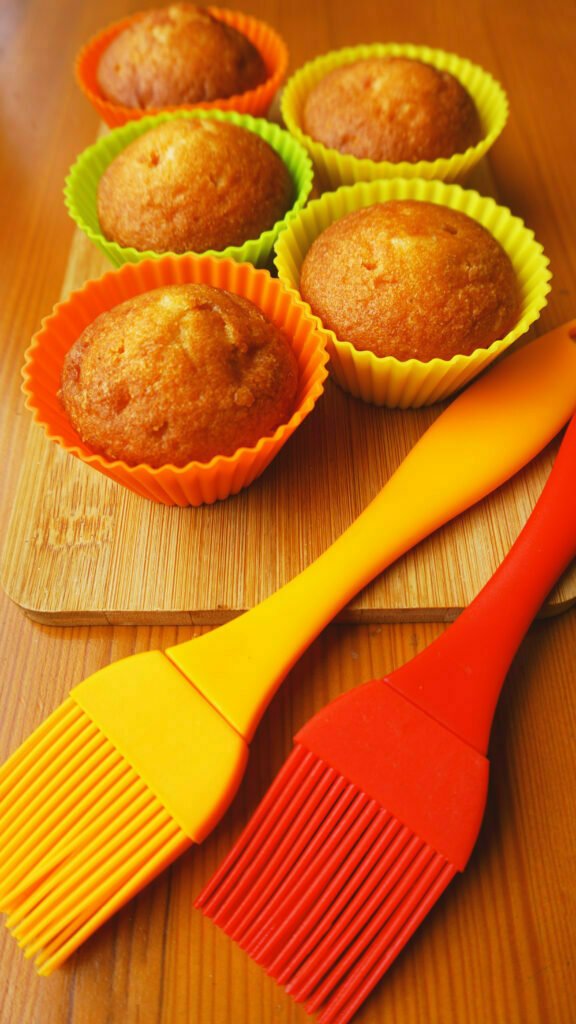 Simple mini muffins in colorful silicone bakeware. Silicone cup baking cupcakes and silicone brushes. Kitchen and cooking concept on wooden background